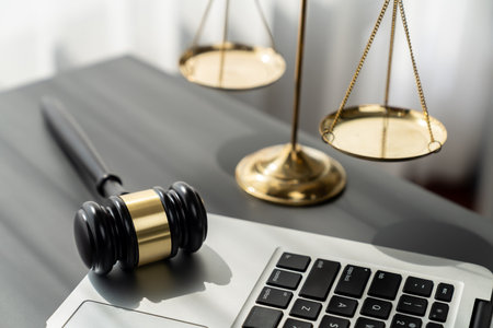 Symbolizing justice and legal authority, golden balanced scale and gavel on desk with laptop in law office background, reflecting concept of equality and fair judgment by lawyer and judge. equilityの写真素材