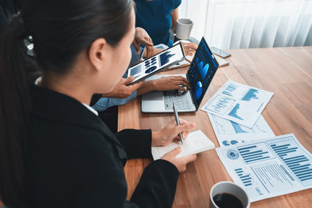 Multiracial analyst team use BI Fintech software to analyze financial data on meeting table. Financial dashboard data display on laptop screen with analyzed chart for marketing indication. Concordの写真素材