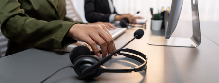 Panorama focus hand holding headset on call center workspace desk with blur background of operator...
