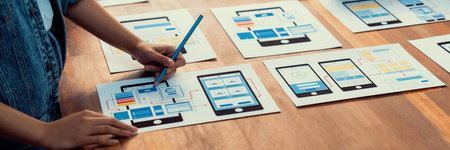 Panorama shot of front-end developer team brainstorming UI and UX designs for mobile app on paper...