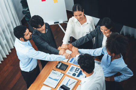 Diverse team of officer workers hold hands in circle, showing solidarity and teamwork in corporate office. Businesspeople form strong community built on integrity and collaboration. Concordの写真素材