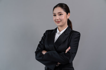 Confident young businesswoman stands on isolated background, posing in formal black suit. Office lady or manager with smart and professional appearance. Enthusiasticの写真素材