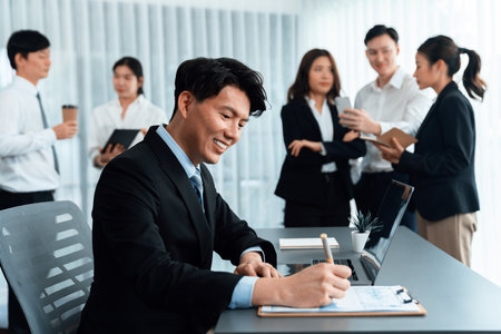 Portrait of focus young successful confident male manager, executive wearing business wear in harmony office arm crossed with blurred meeting background of colleagues, office worker.の写真素材