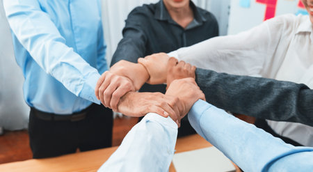 Diverse team of officer workers hold hands in circle, showing solidarity and teamwork in corporate office. Businesspeople form strong community built on integrity and collaboration. Concordの写真素材