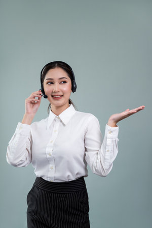 Asian female call center operator with smile face advertises job opportunity, wearing a formal suit and headset holding hand gesture for product on customizable isolated background. Enthusiasticの写真素材