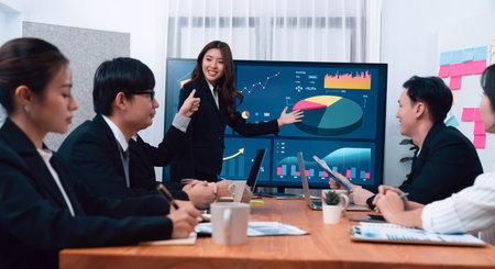 Confidence and young asian businesswoman give presentation on financial business strategy in dashboard report display on screen to colleagues in conference room meeting as harmony in workplace conceptの写真素材