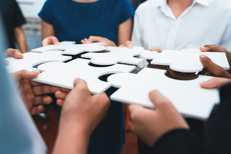 Diverse corporate officer workers collaborate in office, connecting puzzle pieces to represent...
