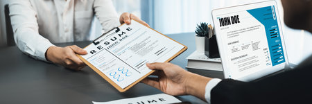 Suit-clad candidate hand over resume to interviewers during job interview in meeting room. Job application and interview for career opportunity in modern office with HR recruitment team. Prodigyの写真素材