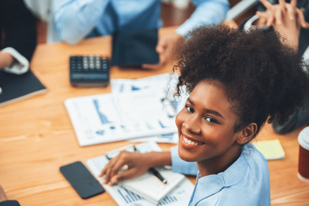 Portrait of happy young african businesswoman with group of office worker on meeting with screen display business dashboard in background. Confident office lady at team meeting. Concordの写真素材