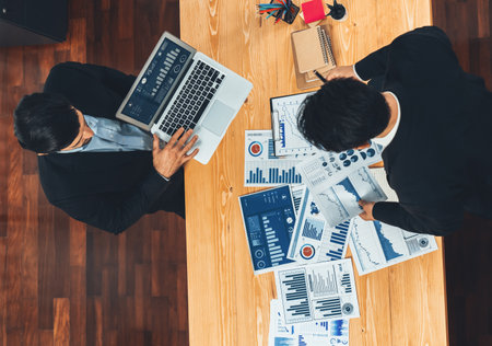 Top view analyst team discussing financial data on digital dashboard, analyzing chart and graph papers by data science software on wooden table background. Business intelligence and Fintech. Ferventの写真素材