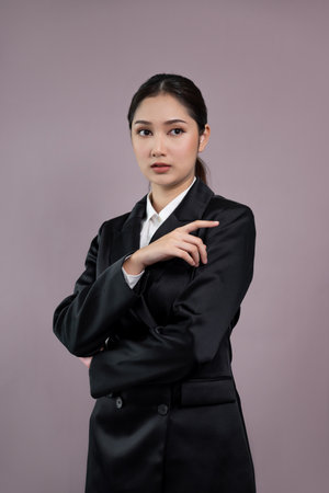 Confident young businesswoman stands on isolated background, posing in formal black suit. Office lady or manager with smart and professional appearance. Enthusiasticの写真素材