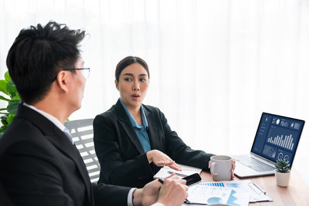 Busy analyst team in office discuss data analysis and marketing strategy using BI dashboard and statistics on laptop screen to improve business performance at meeting with strong teamwork. Jubilantの写真素材