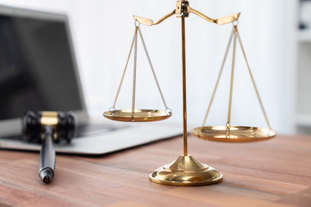 Symbolizing justice and legal authority, golden balanced scale and gavel on desk with laptop in law office background, reflecting concept of equality and fair judgment by lawyer and judge. equilityの写真素材