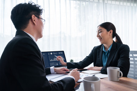 Busy analyst team in office discuss data analysis and marketing strategy using BI dashboard and statistics on laptop screen to improve business performance at meeting with strong teamwork. Jubilantの写真素材