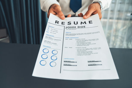 Confident man wearing suit in formal office, hand holding resume paper during job interview....