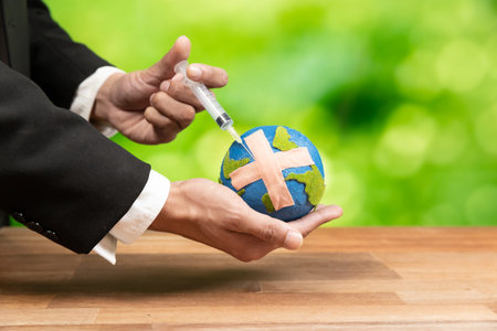 Businessman holds and inject medicine to paper earth as symbol of eco environmental awareness and...