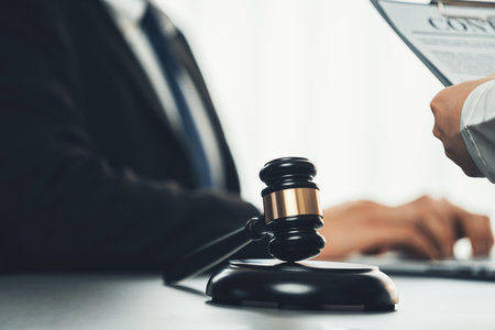 Focus shiny golden balanced scale on blurred background of lawyer colleagues working on desk at law firm office. Scale balance for righteous and equality judgment by lawmaker and attorney. Equilibriumの写真素材