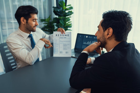 Interviewing job applicant in office with resume paper. Candidate wear suit for formal conversation with interviewer. Recruitment process with question about career and work experience. Ferventの写真素材