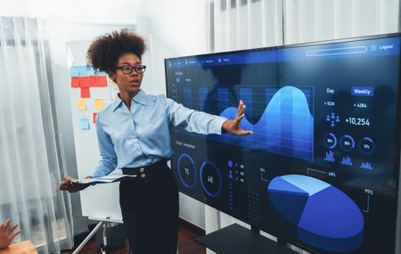 Young african businesswoman presenting data analysis dashboard on TV screen in modern meeting. Business presentation with group of business people in conference room. Concordの写真素材