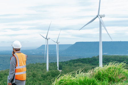 Engineer working on a wind farm atop a hill or mountain in the rural. Progressive ideal for the...