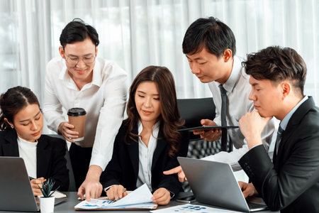 Harmony in office concept as business people analyzing dashboard paper together in workplace. Young colleagues give ideas at manager desk for discussion or strategy planning about project.の写真素材