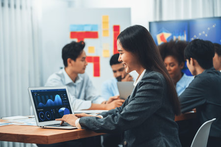 Portrait of happy young asian businesswoman with group of office worker on meeting with screen display business dashboard in background. Confident office lady at team meeting. Concordの写真素材