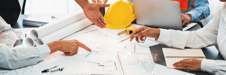 Engineer partner drawing and working on blueprint design together on office table for architectural...