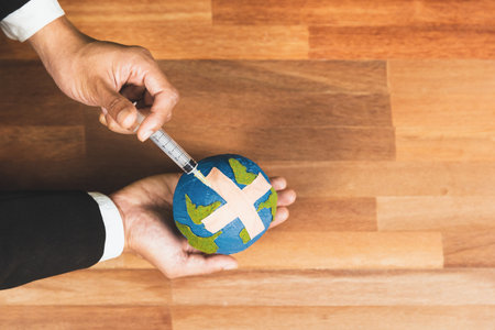 Top view businessman holds and inject medicine to paper earth as symbol of eco environmental...