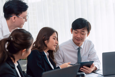 Harmony in office concept as business people analyzing dashboard paper together in workplace. Young colleagues give ideas at manager desk for discussion or strategy planning about project.の写真素材