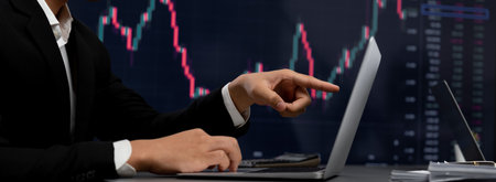 Stock trading investor finger pointing on dynamic financial data graph on monitor. Businessman or...