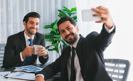 Happy business snapping selfie at office desk after finishing paperwork. Smiling and having fun as friendship and teamwork concept. Professional and friendly environment in workplace. Ferventの写真素材
