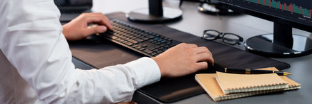 Office worker sitting on workspace desk, focused and engaged, using computer and typing on keyboard to input data ensure accurate data management in the modern workplace. Trailblazingの写真素材