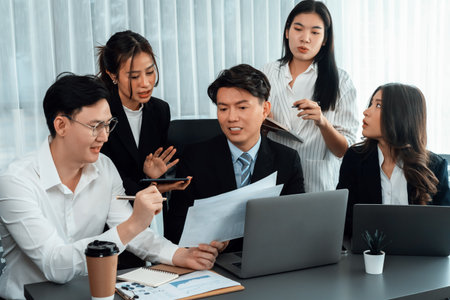 Harmony in office concept as business people analyzing dashboard paper together in workplace. Young colleagues give ideas at manager desk for discussion or strategy planning about project.の写真素材