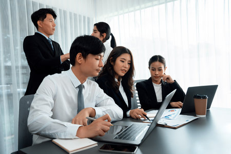 Harmony in office concept as business people analyzing dashboard paper together in workplace. Young colleagues give ideas at manager desk for discussion or strategy planning about project.の写真素材