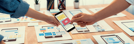 Panorama shot of front-end developer team brainstorming UI and UX designs for mobile app on paper wireframe interface. User interface development team planning for user-friendly UI design. Scrutinizeの写真素材