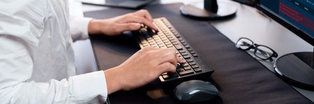 Office worker sitting on workspace desk, focused and engaged, using computer and typing on keyboard...