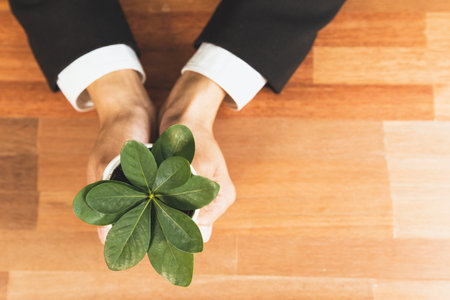 Top view businessman holding plant pot with his hand promoting forest regeneration and eco...