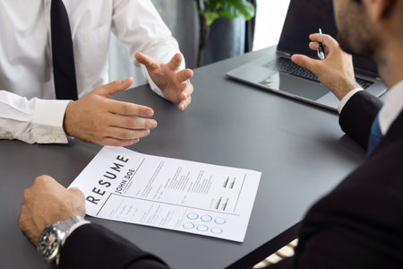 Interviewing job applicant in office with resume paper. Candidate wear suit for formal conversation with interviewer. Recruitment process with question about career and work experience. Ferventの写真素材