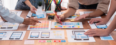 Panorama shot of front-end developer team brainstorming UI and UX designs for mobile app on paper...