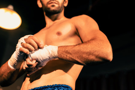 Caucasian boxer portrait with muscular and athletic body wrapping his hand or fist on the ring be...