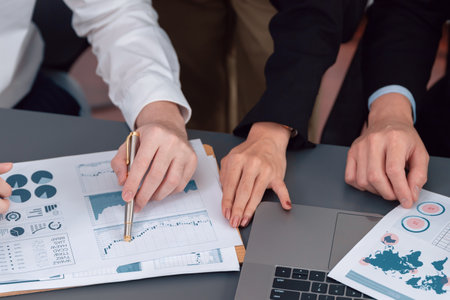 Closeup on BI dashboard on meeting desk with businesspeople analyzing or planning business strategy with hands pointing on financial paper reports as concept of harmony in office workplace.の写真素材
