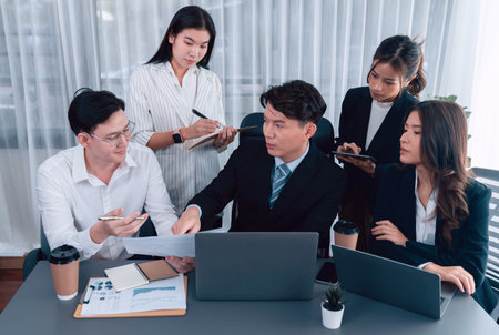 Harmony in office concept as business people analyzing dashboard paper together in workplace. Young colleagues give ideas at manager desk for discussion or strategy planning about project.の写真素材