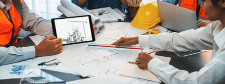 Engineer and architect working together brainstorming and designing blueprint using laptop working...
