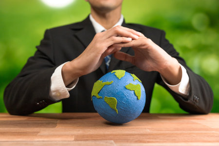 Businessman holds paper earth as symbol of eco environmental awareness for sustainable world using clean energy and zero CO2 emission. Eco-friendly corporate with go green policy to save earth. Alterの写真素材