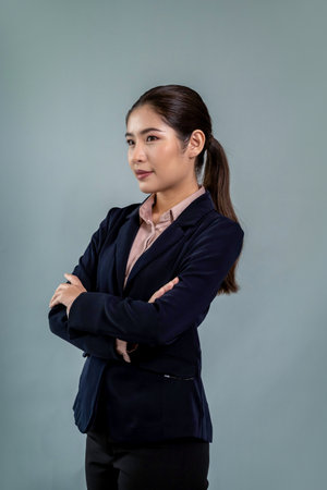 Confident young businesswoman stands on isolated background, posing in formal black suit. Office lady or manager with smart and professional appearance. Enthusiasticの写真素材
