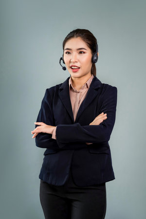Attractive asian female call center operator with happy smile face advertises job opportunity on empty space, wearing a formal suit and headset on customizable isolated background. Enthusiasticの写真素材