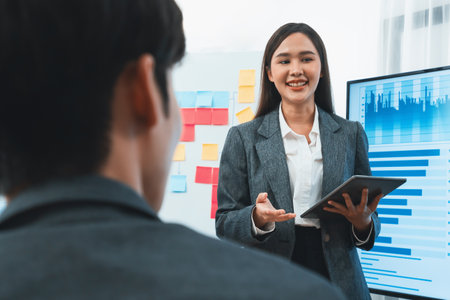 Young asian businesswoman presenting data analysis dashboard on TV screen in modern meeting. Business presentation with group of business people in conference room. Concordの写真素材