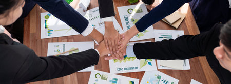 Group of business people put hand stack showing synergy of corporate cooperation on environmental...