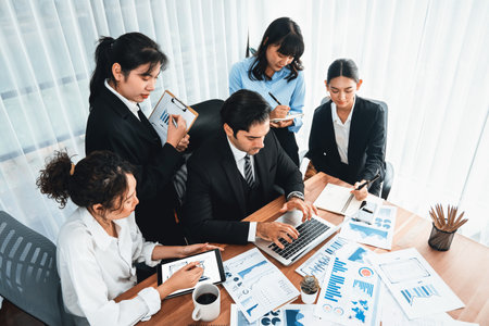 Diverse group of business analyst team analyzing financial data report paper on office table. Chart and graph dashboard by business intelligence analysis for strategic marketing planning Meticulousの写真素材