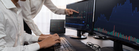 Group of traders discussing on office desk, monitoring stock market on monitor at office workplace. Businessman and broker analyzing stock graph together at stock trading company. Trailblazingの写真素材